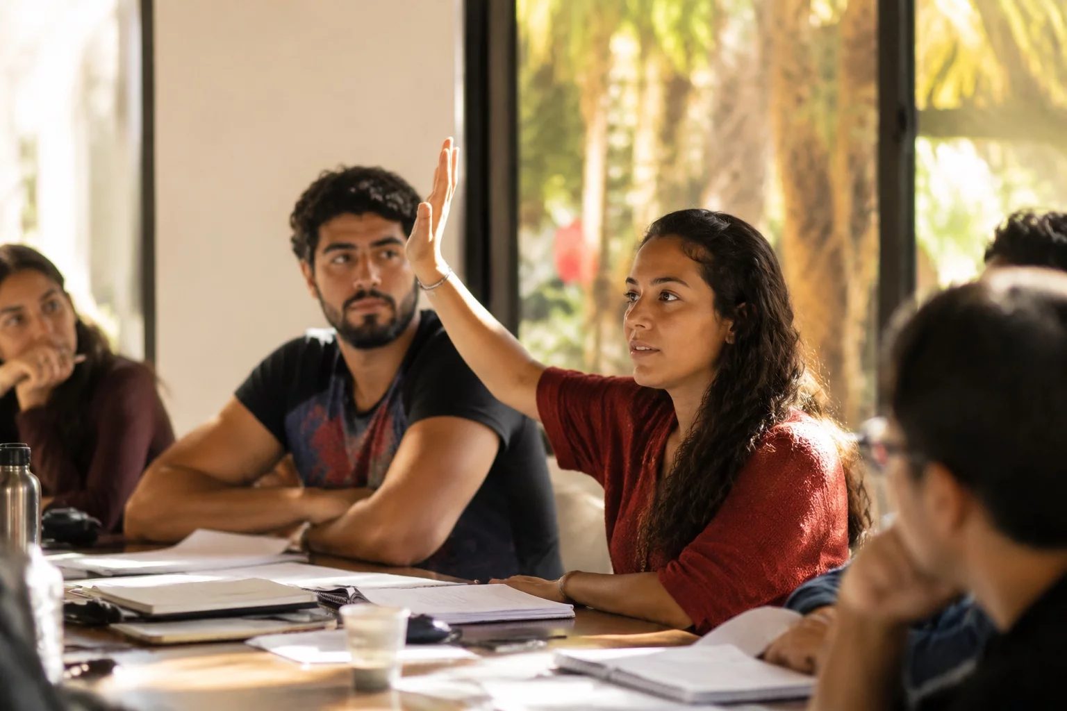 Estudante levantando a mão em uma mesa de seminário coberta de anotações